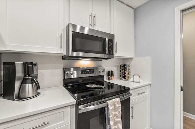 kitchen with white cabinets, tasteful backsplash, stainless steel appliances, and light countertops