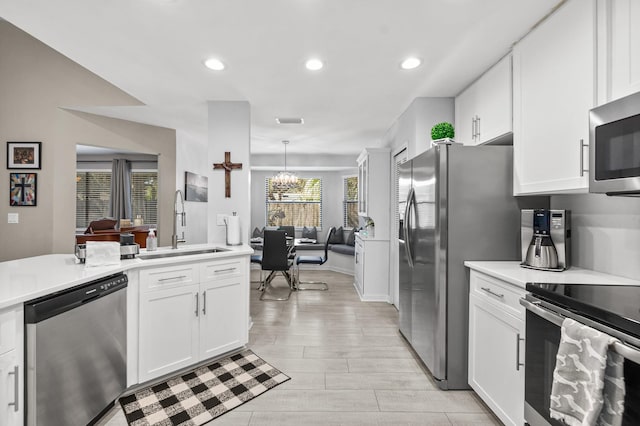 kitchen with stainless steel appliances, an inviting chandelier, a sink, and white cabinets