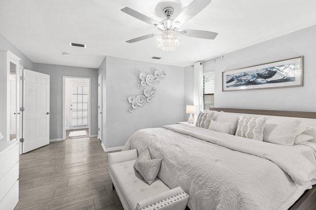 bedroom featuring a ceiling fan, baseboards, visible vents, and wood finished floors