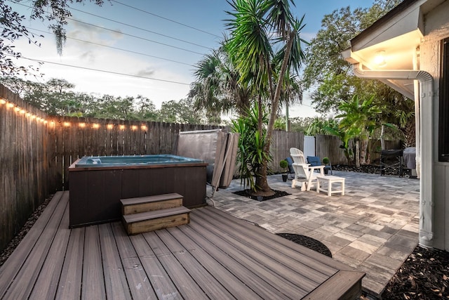 deck featuring a patio area, a fenced backyard, and a hot tub