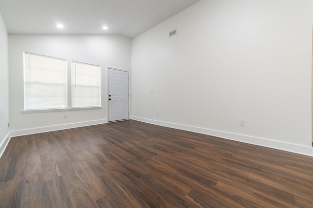 empty room featuring baseboards, vaulted ceiling, dark wood finished floors, and recessed lighting