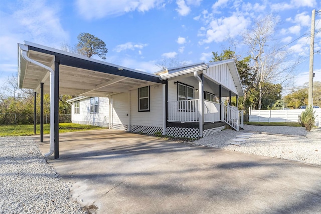 view of front facade with a carport, a porch, fence, and driveway