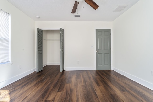 unfurnished bedroom with dark wood-type flooring, a closet, and visible vents