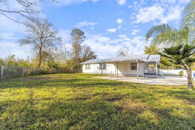 back of house featuring metal roof, a lawn, and fence private yard