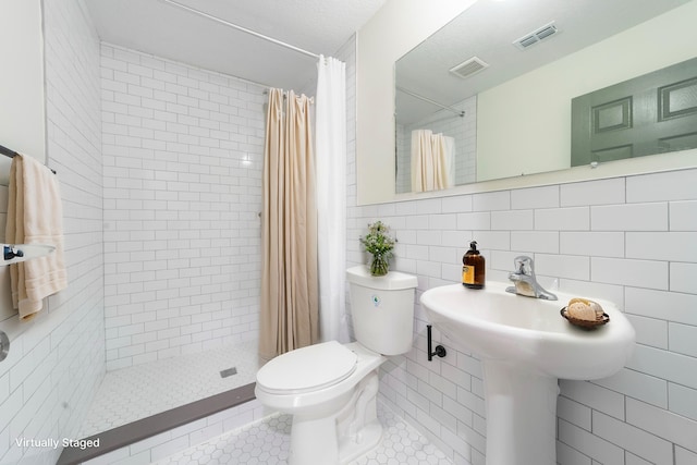 full bathroom with visible vents, toilet, tile patterned flooring, a shower stall, and tile walls