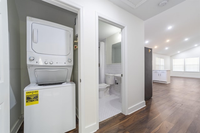 clothes washing area featuring dark wood finished floors, stacked washer and dryer, recessed lighting, laundry area, and baseboards