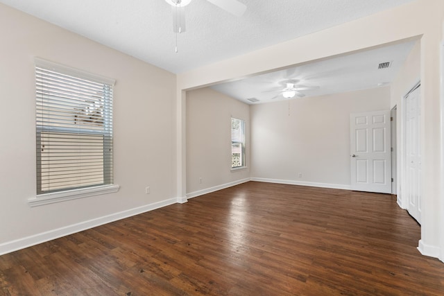 unfurnished room with ceiling fan, a textured ceiling, wood finished floors, visible vents, and baseboards