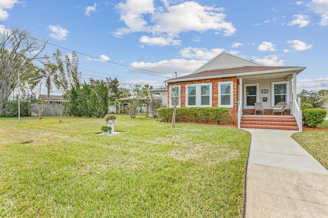 view of front of property with covered porch, brick siding, fence, and a front lawn