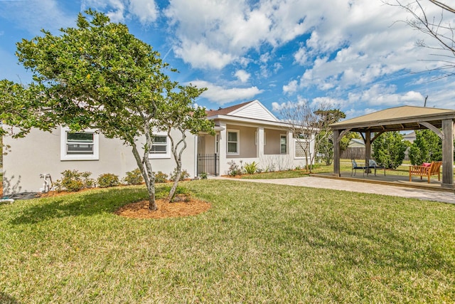 view of front of property featuring fence, a front yard, a gazebo, stucco siding, and a patio area