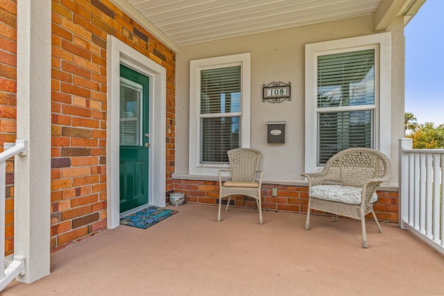 property entrance featuring a porch and brick siding