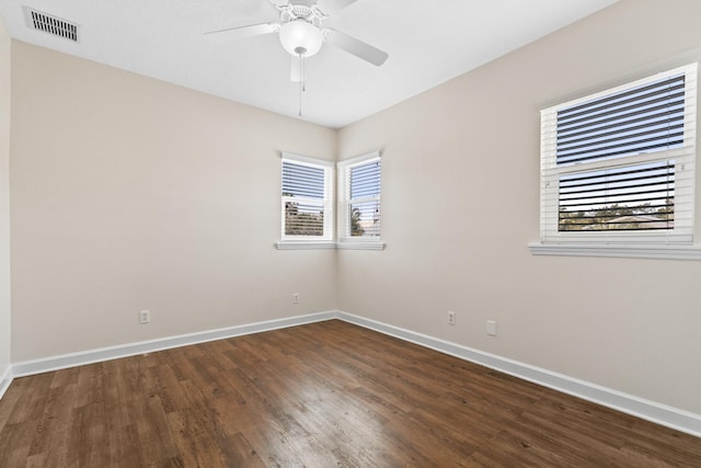 spare room with ceiling fan, dark wood-type flooring, visible vents, and baseboards