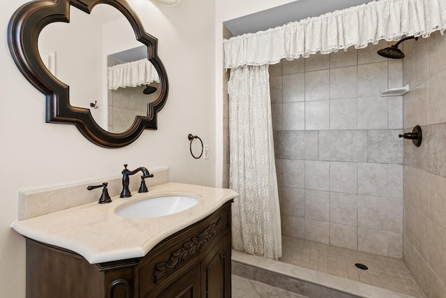 full bathroom featuring tiled shower and vanity