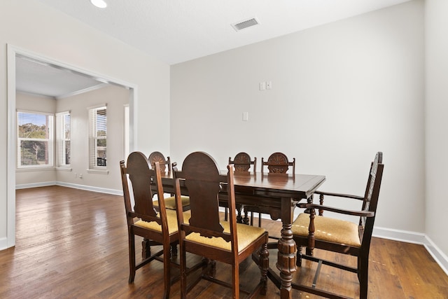 dining space featuring dark wood-type flooring, visible vents, and baseboards