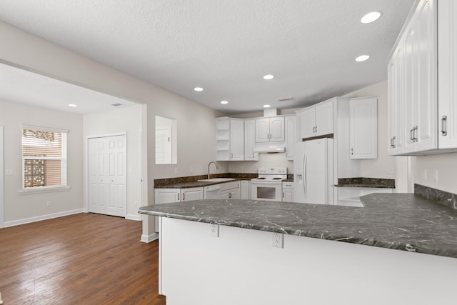 kitchen featuring a peninsula, white appliances, white cabinetry, and under cabinet range hood