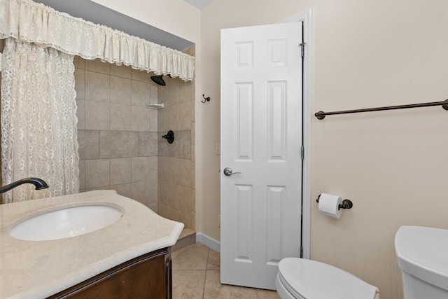 bathroom featuring vanity, tiled shower, tile patterned flooring, and toilet