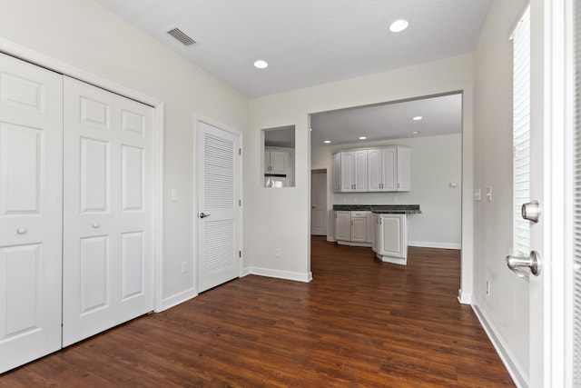 corridor featuring recessed lighting, visible vents, dark wood finished floors, and baseboards