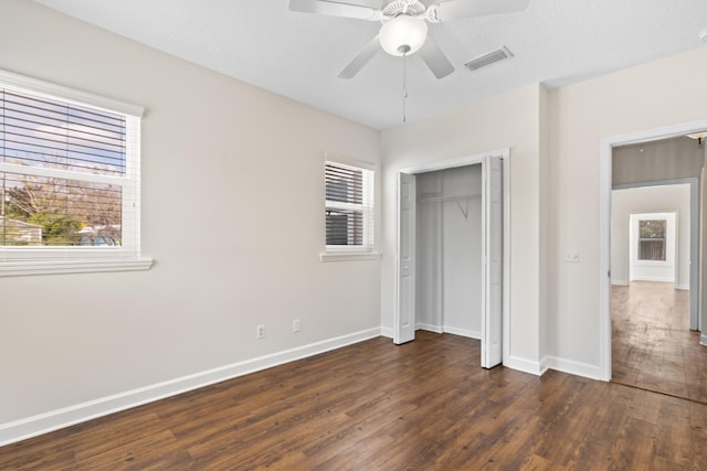 unfurnished bedroom with ceiling fan, visible vents, baseboards, a closet, and dark wood finished floors