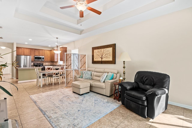 tiled living room with a raised ceiling and ceiling fan