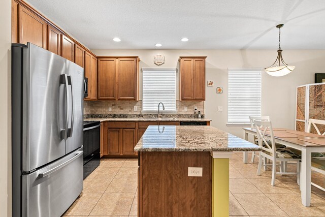 kitchen featuring stainless steel fridge, sink, pendant lighting, black range, and a center island