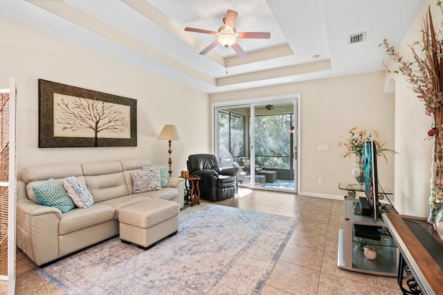 tiled living room featuring a tray ceiling and ceiling fan