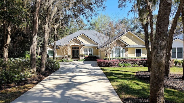 craftsman inspired home with stone siding, stucco siding, driveway, and a front yard