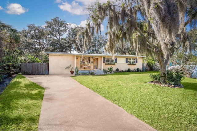 view of front of property featuring covered porch, fence, stucco siding, and a front yard