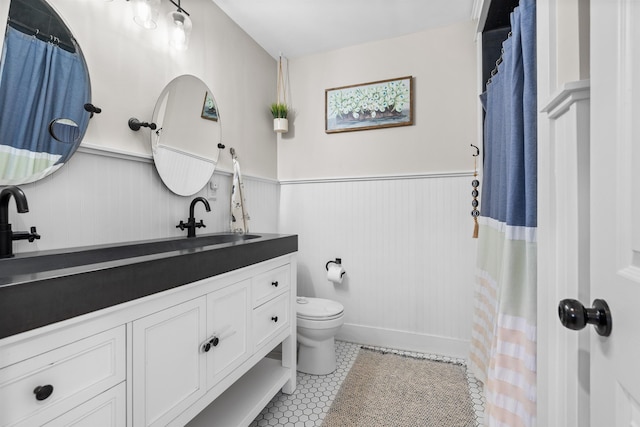 bathroom with toilet, a wainscoted wall, tile patterned floors, vanity, and a shower with curtain