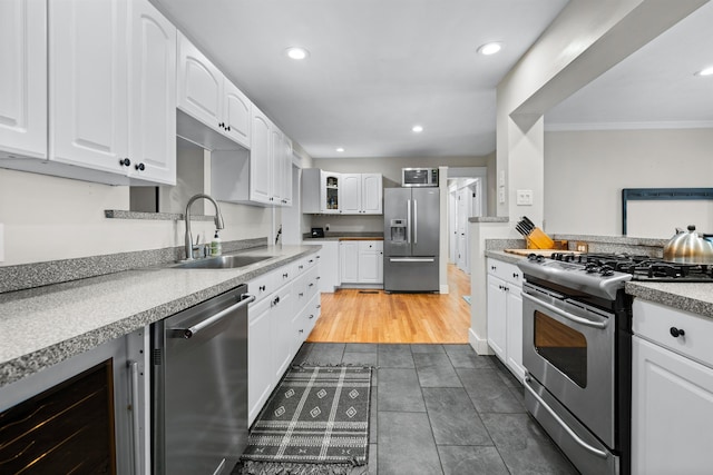 kitchen with appliances with stainless steel finishes, glass insert cabinets, white cabinets, a sink, and beverage cooler