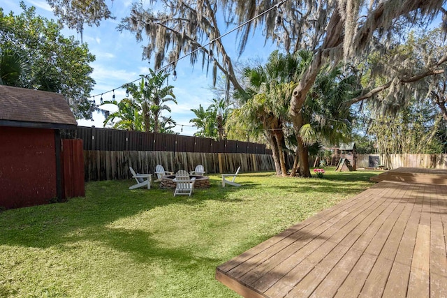 view of yard featuring an outdoor fire pit, a fenced backyard, and a deck