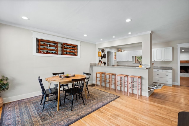 dining area featuring light wood-style flooring, baseboards, and crown molding