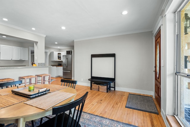 dining area with light wood-type flooring, baseboards, and crown molding