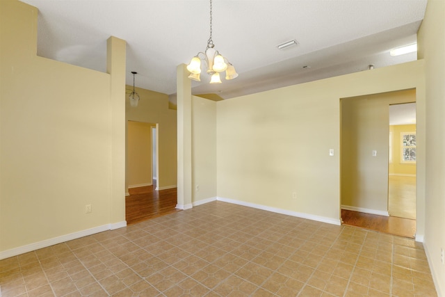 unfurnished room with an inviting chandelier, baseboards, and visible vents