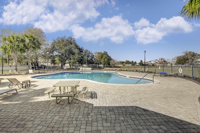 community pool with a patio area and fence