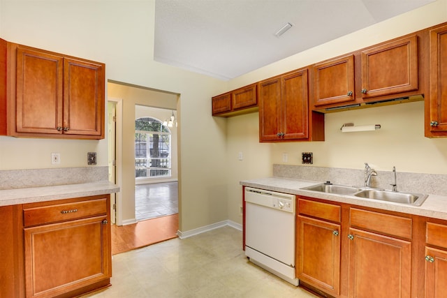 kitchen with baseboards, light countertops, white dishwasher, brown cabinetry, and a sink