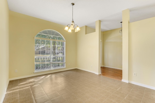 spare room with baseboards and an inviting chandelier