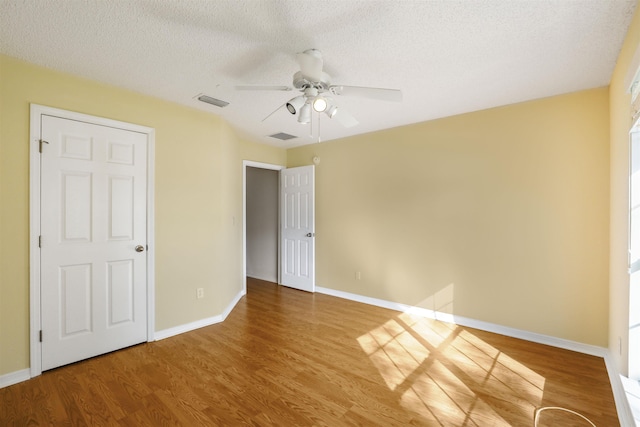 unfurnished bedroom with a textured ceiling, baseboards, and wood finished floors