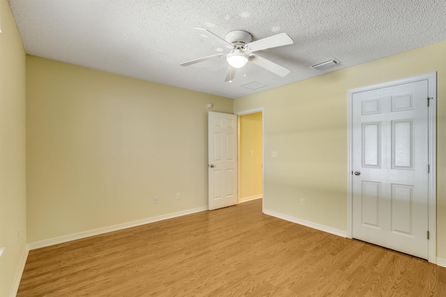 unfurnished bedroom with light wood finished floors, visible vents, baseboards, a textured ceiling, and a ceiling fan