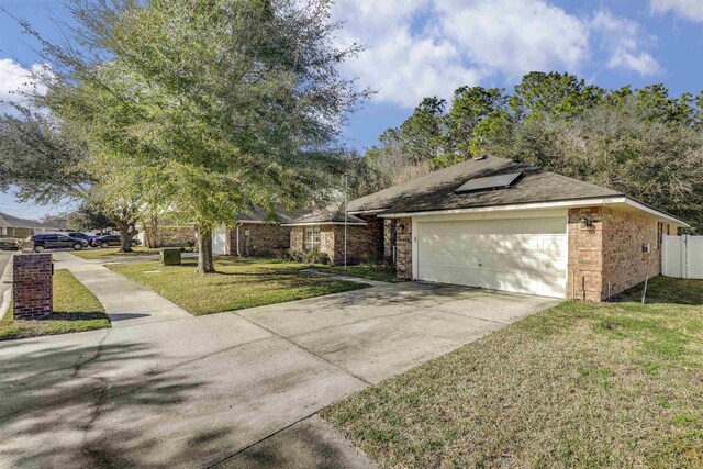 view of side of home featuring driveway, a yard, a garage, brick siding, and solar panels