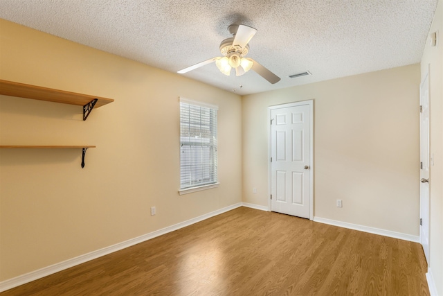 unfurnished bedroom with visible vents, baseboards, a textured ceiling, and wood finished floors