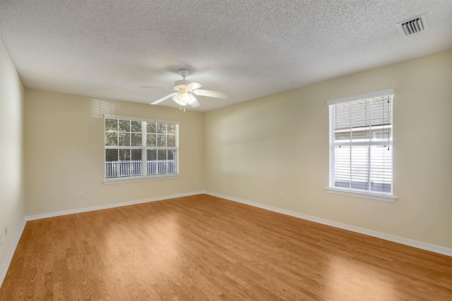 spare room with light wood-type flooring, visible vents, plenty of natural light, and a ceiling fan