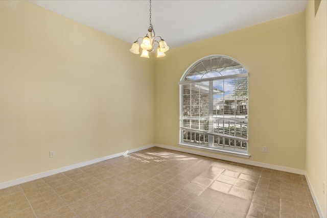 spare room with an inviting chandelier and baseboards