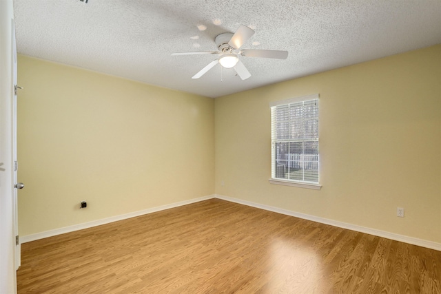 unfurnished room featuring baseboards, light wood-style floors, a ceiling fan, and a textured ceiling