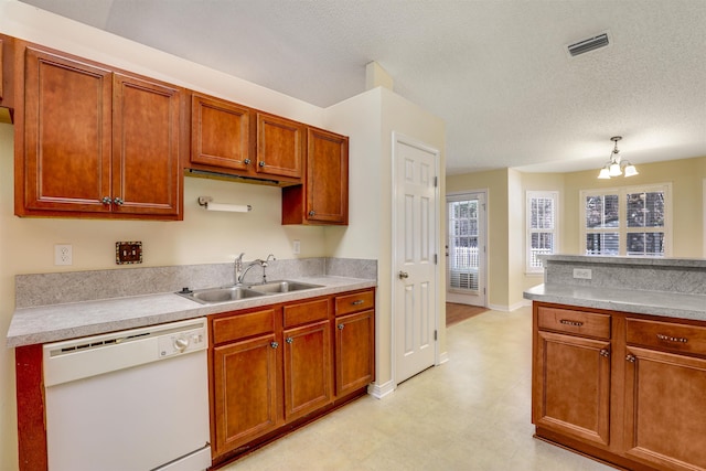 kitchen featuring dishwasher, light countertops, visible vents, and a sink