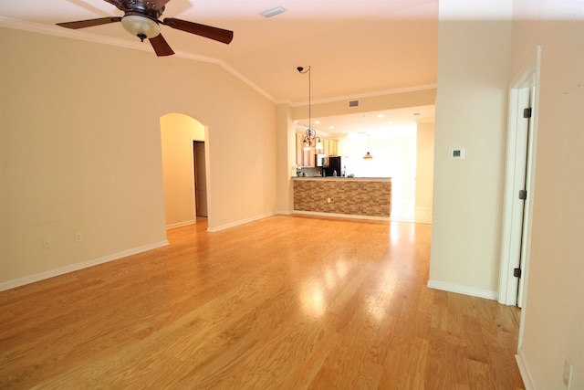 unfurnished living room with ceiling fan, arched walkways, ornamental molding, visible vents, and vaulted ceiling