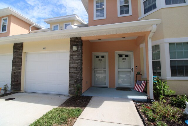 view of exterior entry featuring driveway, stucco siding, and stone siding