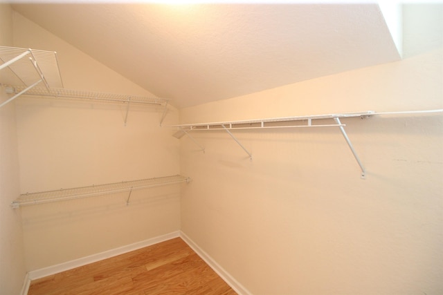 spacious closet with light wood-style flooring and lofted ceiling
