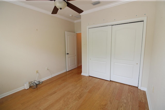 unfurnished bedroom featuring crown molding, light wood-type flooring, a closet, visible vents, and baseboards