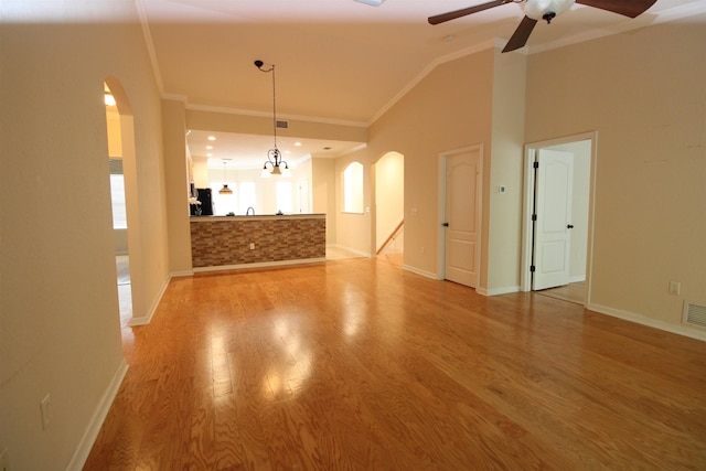 unfurnished living room featuring crown molding, ceiling fan, light wood-style flooring, arched walkways, and lofted ceiling