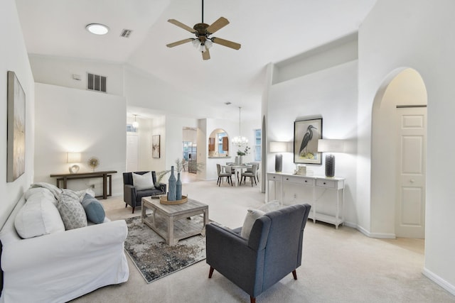 living room with arched walkways, ceiling fan with notable chandelier, visible vents, and light colored carpet