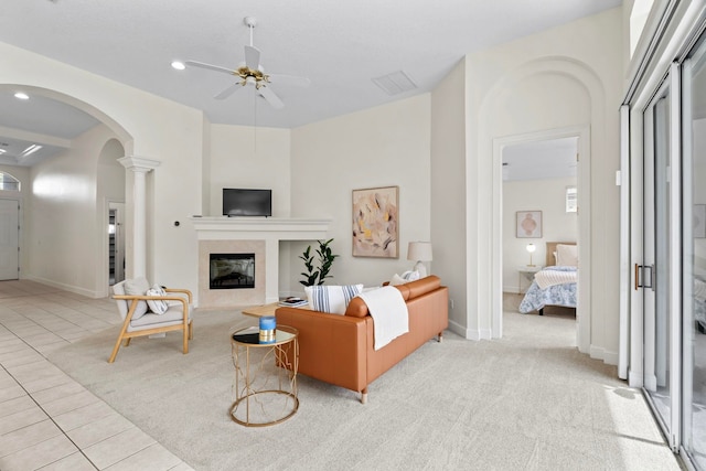 tiled living room with a fireplace, ceiling fan, and ornate columns